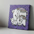 Canvas print with two elephants on a purple background with black spots, placed on a wooden surface.