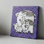Canvas print with two elephants on a purple background with black spots, placed on a wooden surface.